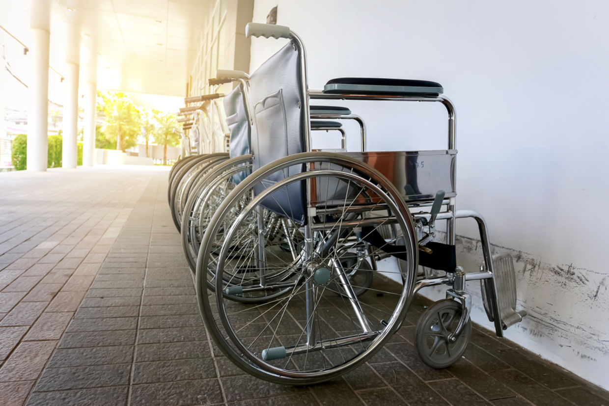 A row of wheelchairs stands next to a wall A row of wheelchairs stands next to a wall