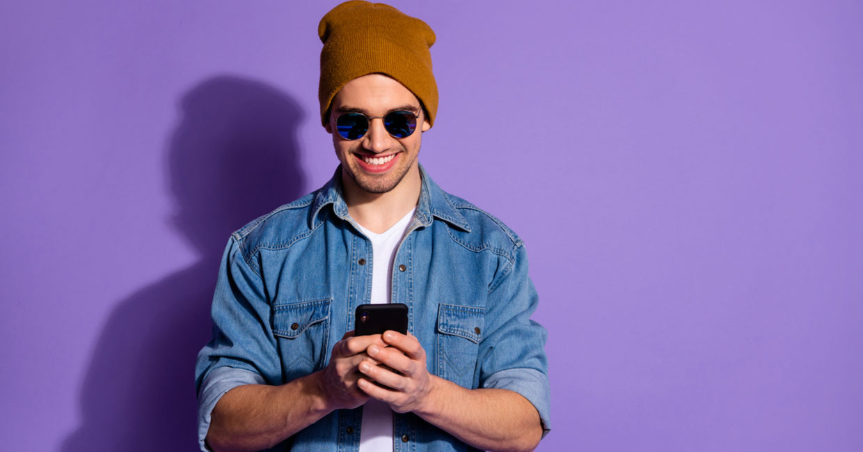 Smiling man on cellphone creates positivity using social media. Smiling man on cellphone creates positivity using social media.