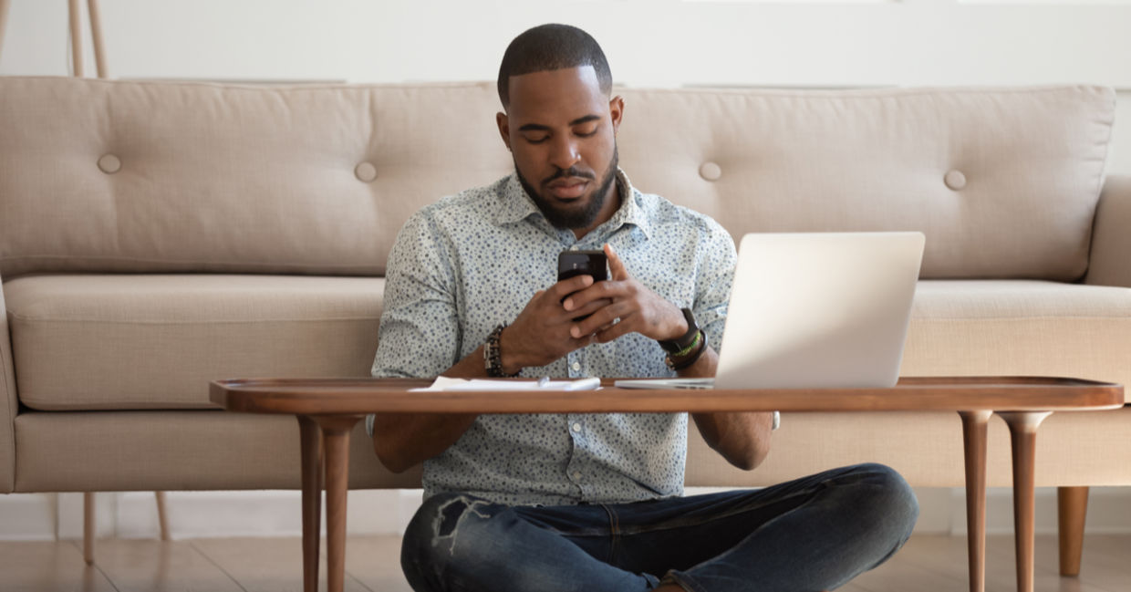 Man working leaned on couch cross-legged near coffee table Man working leaned on couch cross-legged near coffee table