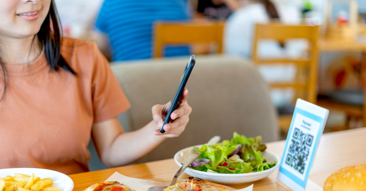 Woman using her smartphone to scan a food menu. Woman using her smartphone to scan a food menu.