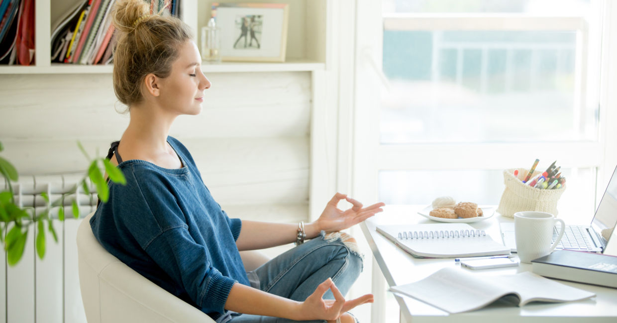 Woman doing yoga at her home office desk. Woman doing yoga at her home office desk.