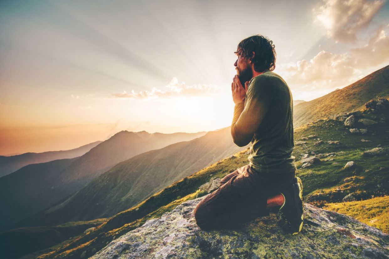 A man sits at sunset in the mountains. A man sits at sunset in the mountains.